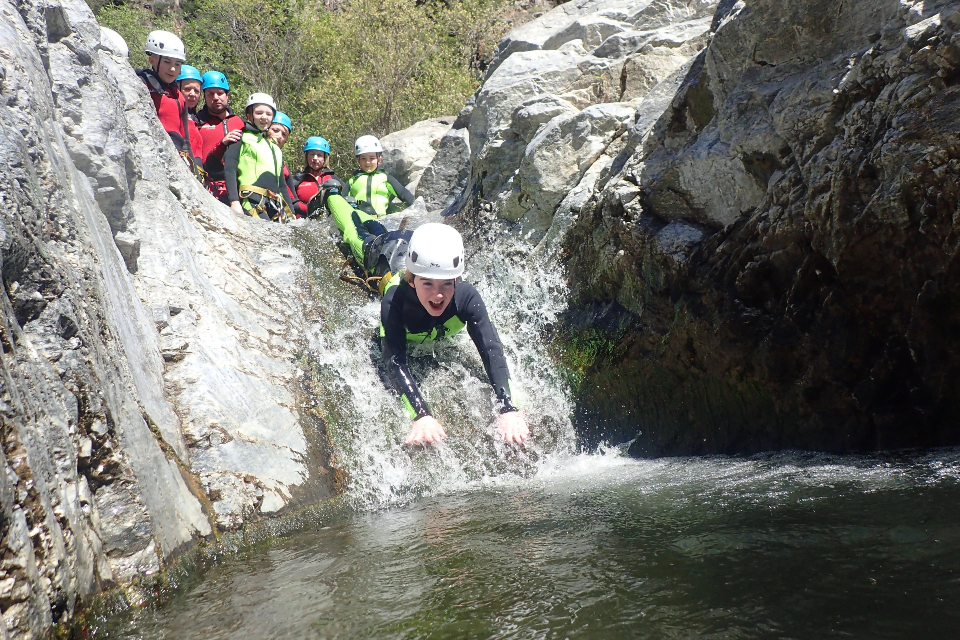 Teenager sliding down a natural rock waterslide on the Guadalmina canyoning tour