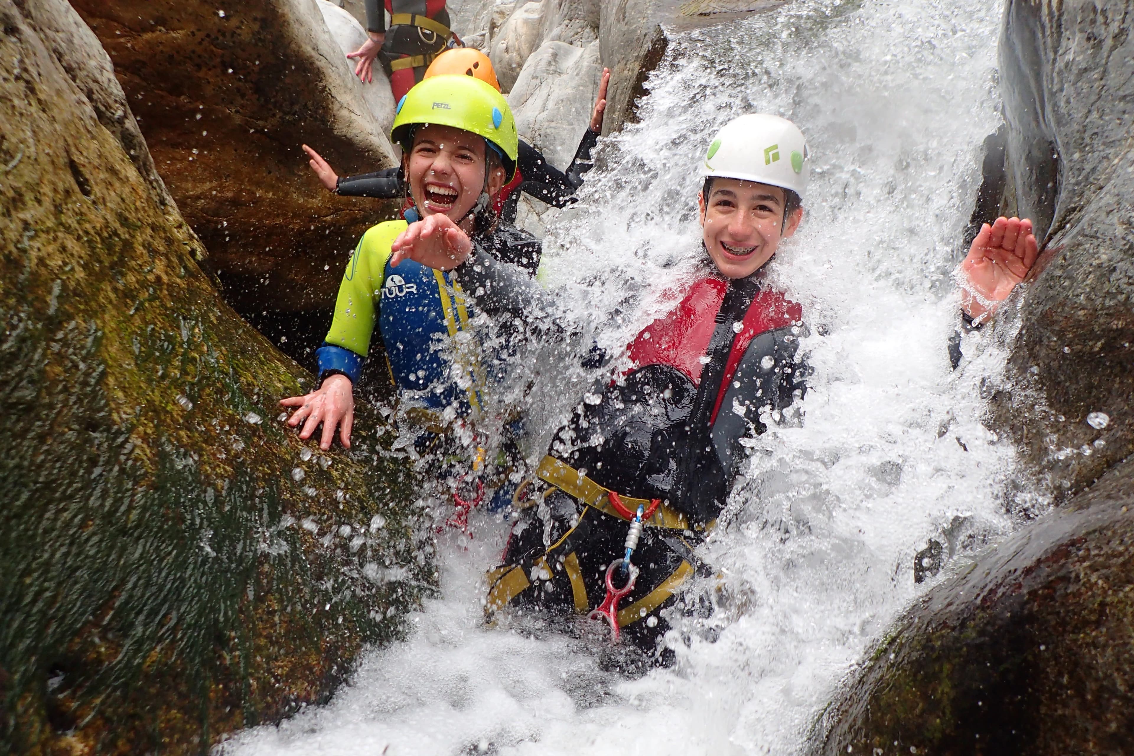 Kids laughing under a waterfall on a family-friendly Benahavís canyoning trip