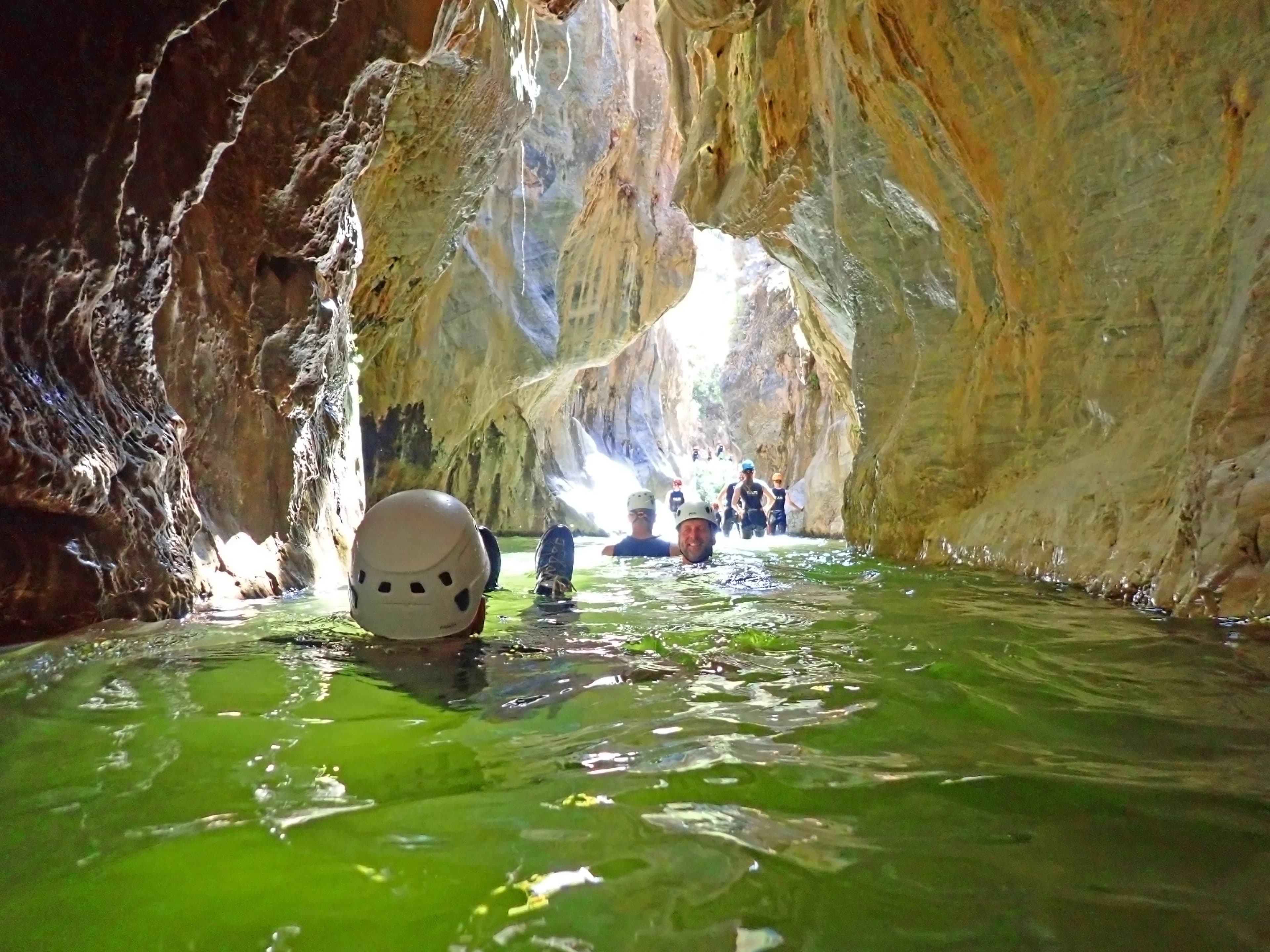 Guide and group swimming through the green waters of the Guadalmina canyon
